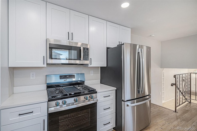 kitchen featuring light wood-style flooring, appliances with stainless steel finishes, white cabinets, and light countertops