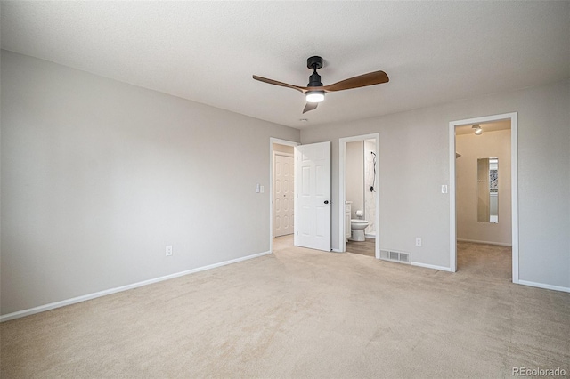 unfurnished bedroom with baseboards, visible vents, ensuite bath, a spacious closet, and light colored carpet