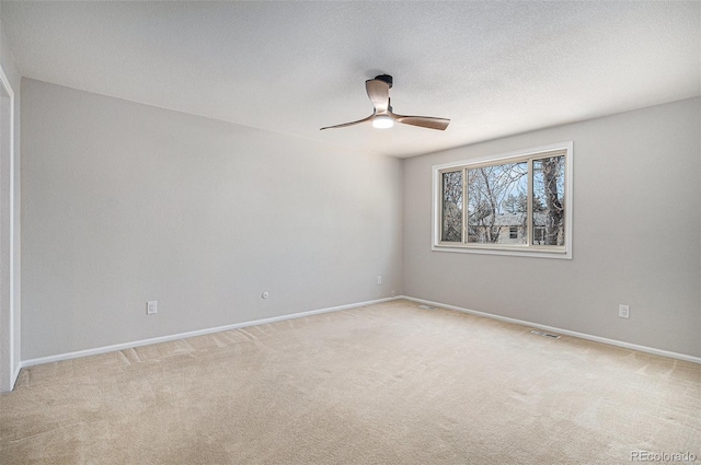 empty room with visible vents, light carpet, a ceiling fan, a textured ceiling, and baseboards