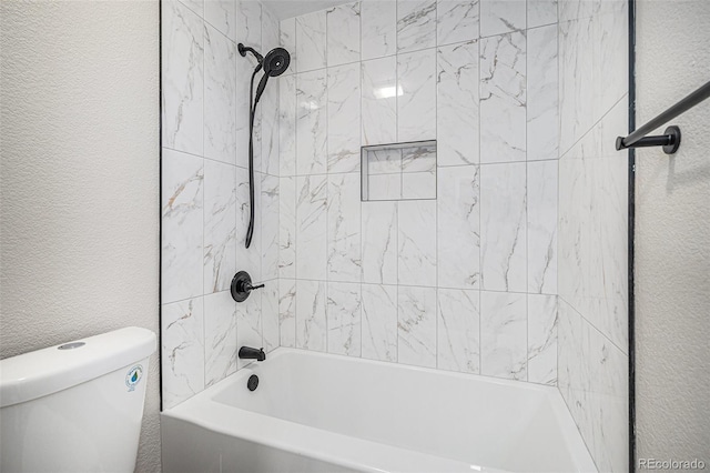 full bathroom with washtub / shower combination, toilet, and a textured wall