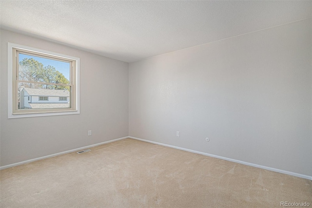 unfurnished room with visible vents, light carpet, a textured ceiling, and baseboards