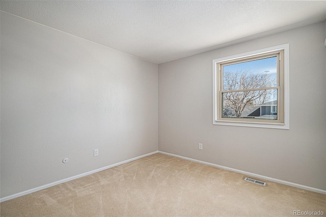 carpeted empty room with visible vents, a textured ceiling, and baseboards