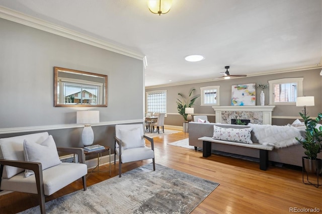 interior space with wood finished floors, a ceiling fan, baseboards, a high end fireplace, and crown molding