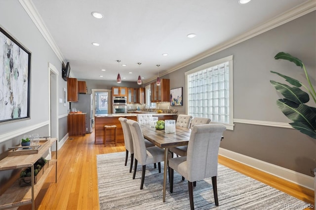 dining room with light wood-type flooring, crown molding, baseboards, and recessed lighting