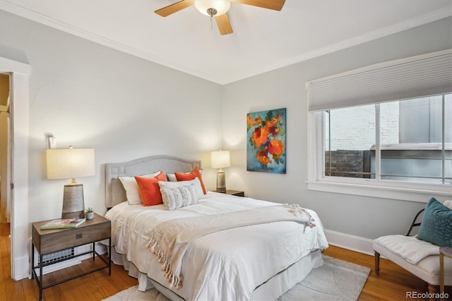 bedroom featuring crown molding, wood finished floors, a ceiling fan, and baseboards