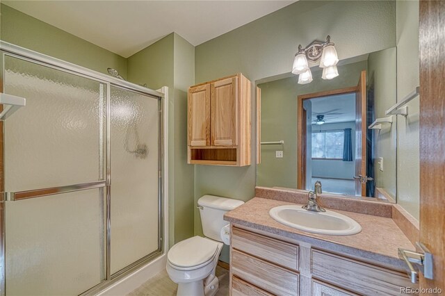 bathroom featuring toilet, vanity, and a shower with shower door