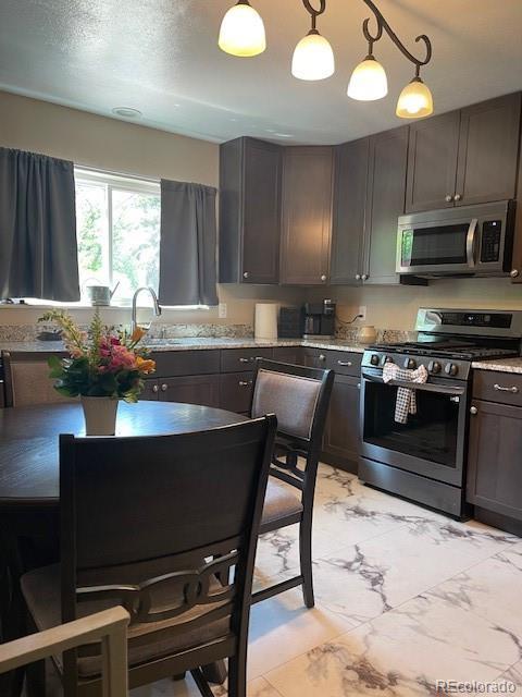 1473 S Monaco Pkwy S, Denver, CO 80224 - kitchen featuring appliances with stainless steel finishes, light marble finish flooring, decorative light fixtures, and a sink