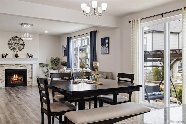 dining area with recessed lighting, a fireplace, light wood-type flooring, and a notable chandelier
