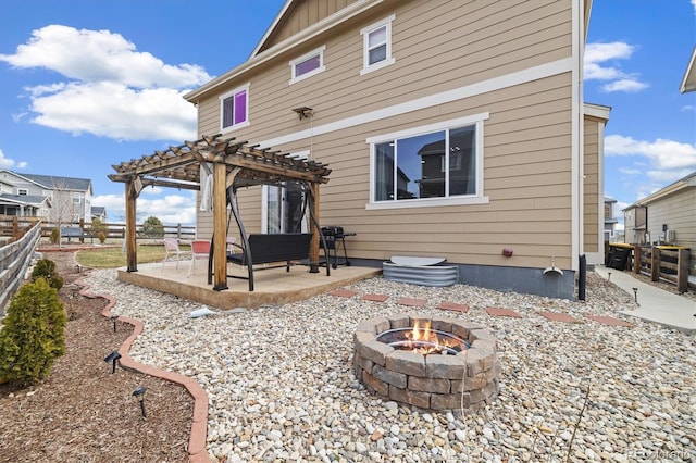 back of house featuring a pergola, a patio, a fenced backyard, board and batten siding, and an outdoor fire pit