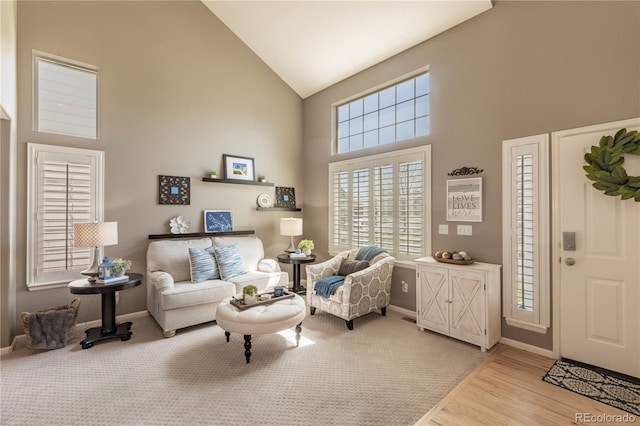 living room with high vaulted ceiling, baseboards, and wood finished floors