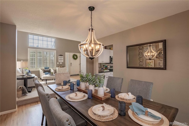 dining room with light wood-style flooring, a notable chandelier, and baseboards
