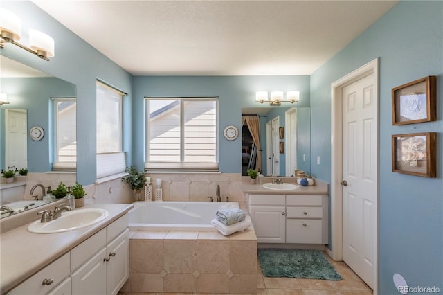 bathroom with a sink, two vanities, tile patterned flooring, and a bath