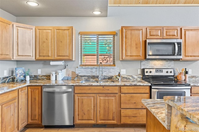 kitchen with light stone counters, appliances with stainless steel finishes, and sink