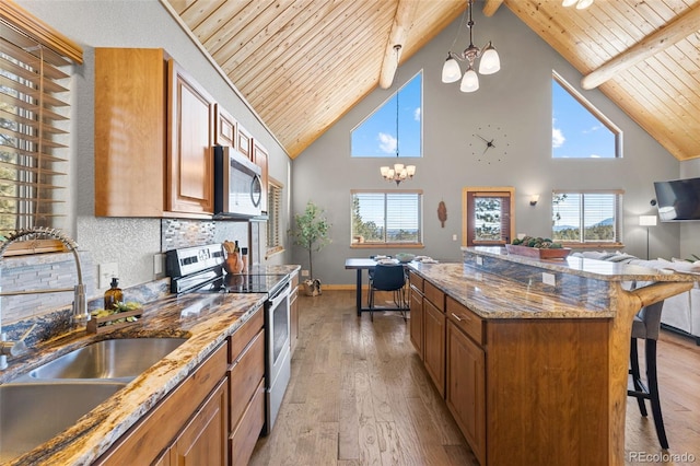 kitchen featuring pendant lighting, sink, appliances with stainless steel finishes, an inviting chandelier, and a kitchen bar