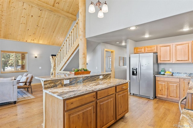 kitchen featuring a kitchen island, stainless steel fridge with ice dispenser, light stone counters, wood ceiling, and light wood-type flooring