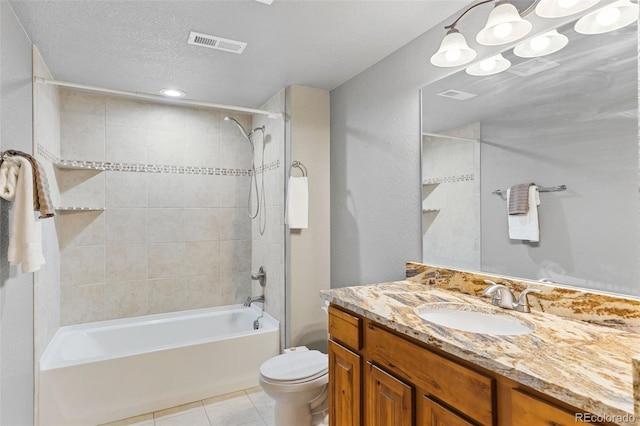 full bathroom featuring tile patterned flooring, vanity, tiled shower / bath combo, toilet, and a textured ceiling