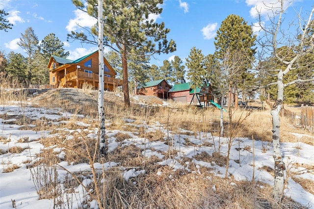 yard covered in snow featuring a wooden deck and a playground