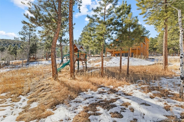 yard covered in snow featuring a playground