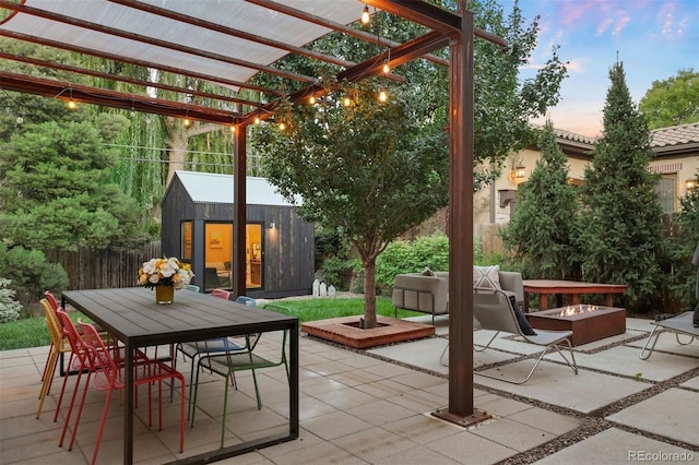 patio terrace at dusk with a pergola, fence, an outbuilding, and outdoor dining area