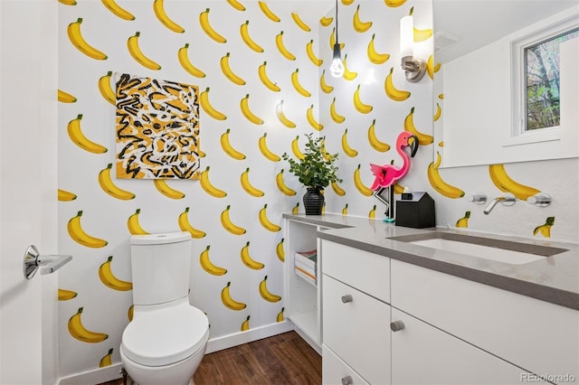 half bathroom featuring toilet, baseboards, wood finished floors, and vanity