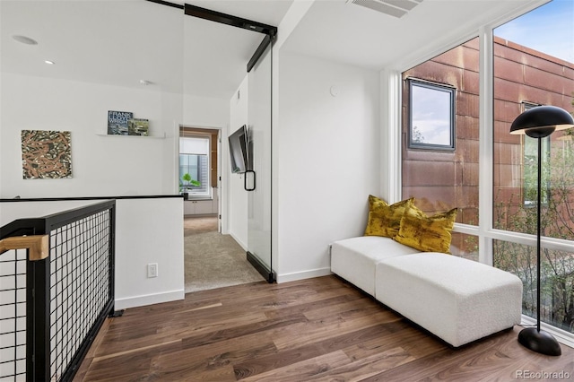 hallway with baseboards, visible vents, and wood finished floors