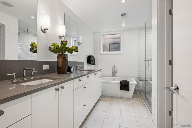 full bathroom featuring visible vents, a sink, a freestanding bath, and a stall shower