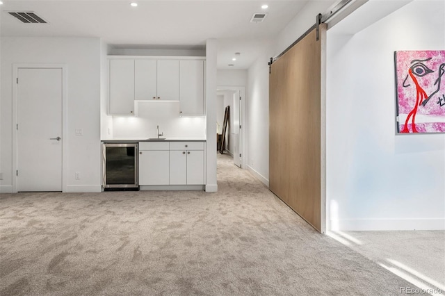 kitchen with beverage cooler, light colored carpet, visible vents, and a barn door