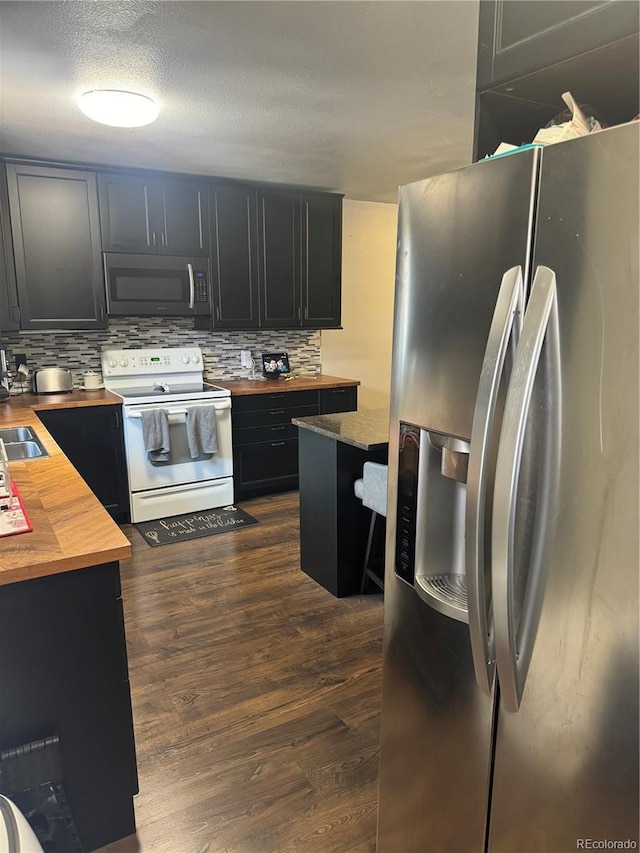 1254 S Reed St Unit 1, Lakewood, CO 80232 - kitchen with butcher block counters, appliances with stainless steel finishes, dark cabinets, decorative backsplash, and a textured ceiling