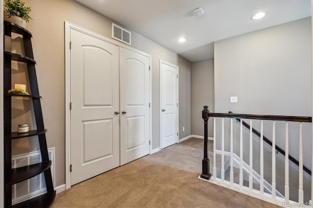 hallway featuring recessed lighting, visible vents, light colored carpet, and an upstairs landing