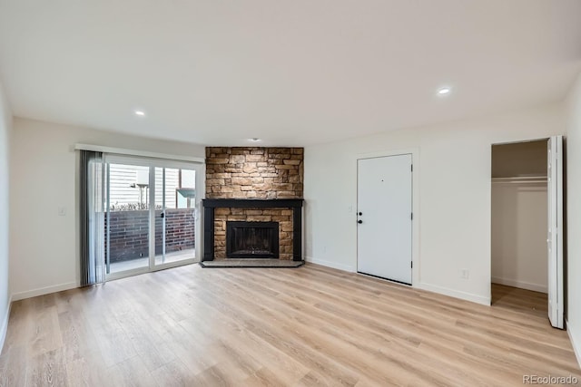 unfurnished living room with baseboards, a stone fireplace, recessed lighting, and light wood-style floors