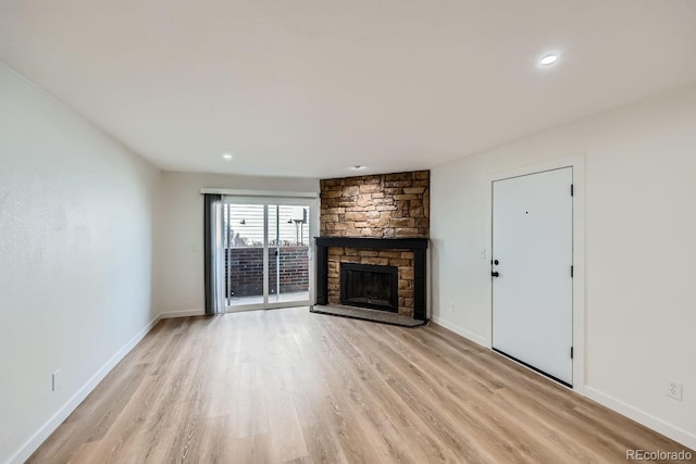 unfurnished living room featuring light wood finished floors, recessed lighting, baseboards, and a stone fireplace