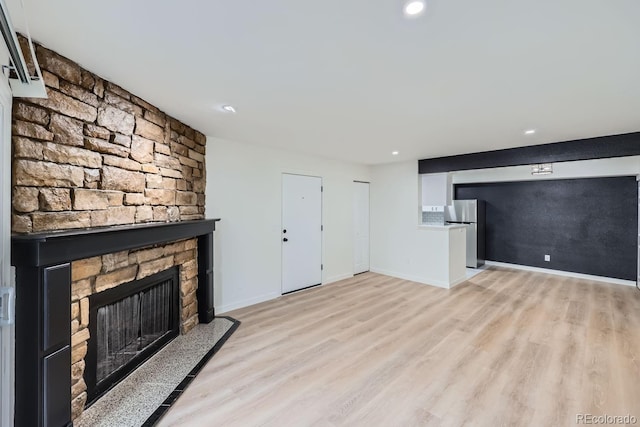 unfurnished living room with light wood-style flooring, a fireplace, baseboards, and recessed lighting