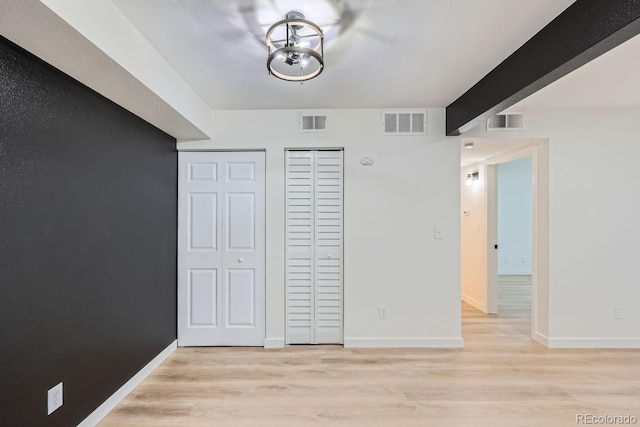 unfurnished bedroom featuring light wood-type flooring, visible vents, and baseboards