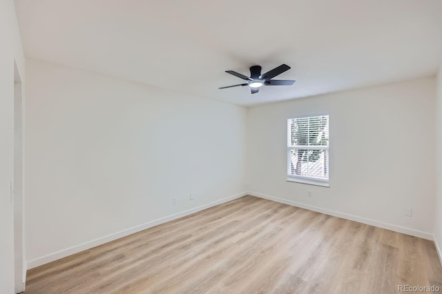 spare room with a ceiling fan, light wood-style flooring, and baseboards