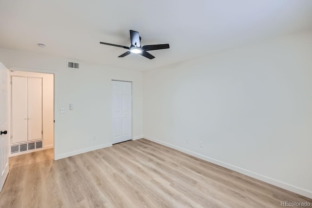 empty room featuring light wood finished floors, baseboards, visible vents, and ceiling fan