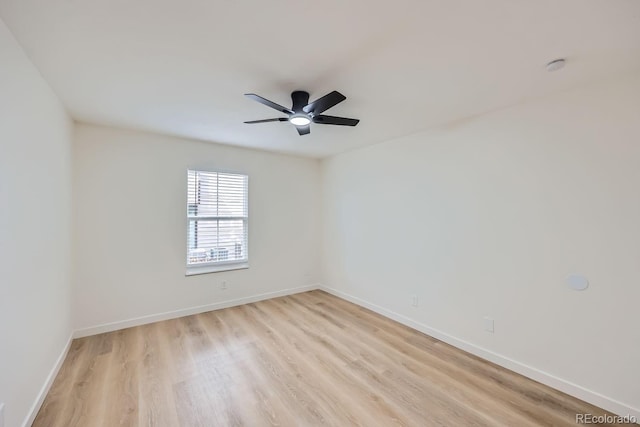 spare room featuring ceiling fan, light wood-style flooring, and baseboards