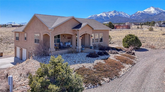 view of front of property with stucco siding, a mountain view, concrete driveway, and an attached garage