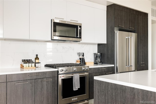 kitchen with stainless steel appliances, tasteful backsplash, white cabinets, and dark brown cabinetry