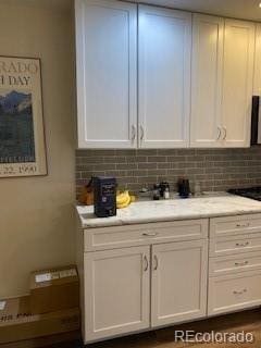 9060 E Cherry Creek S Drive E, Denver, CO 80231 - kitchen featuring white cabinets, light countertops, and decorative backsplash