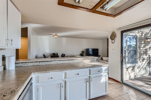 kitchen featuring white cabinets, open floor plan, a peninsula, light stone countertops, and light tile patterned flooring