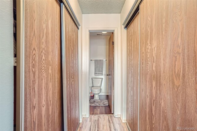 hallway with a textured ceiling and wood finished floors