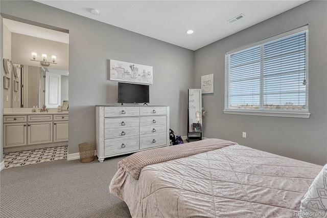 bedroom featuring connected bathroom, sink, and light colored carpet