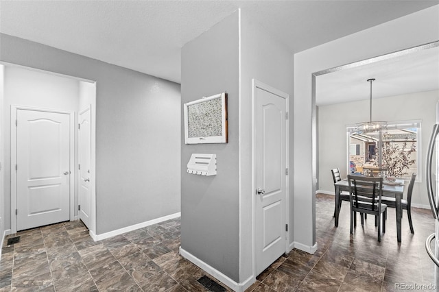 hallway featuring a textured ceiling and an inviting chandelier