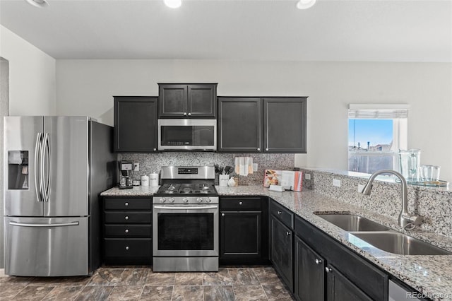 kitchen featuring sink, backsplash, light stone counters, and appliances with stainless steel finishes