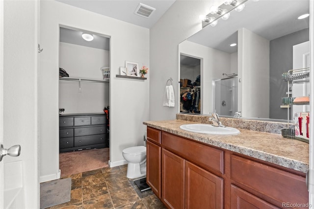 bathroom with walk in shower, vanity, and toilet