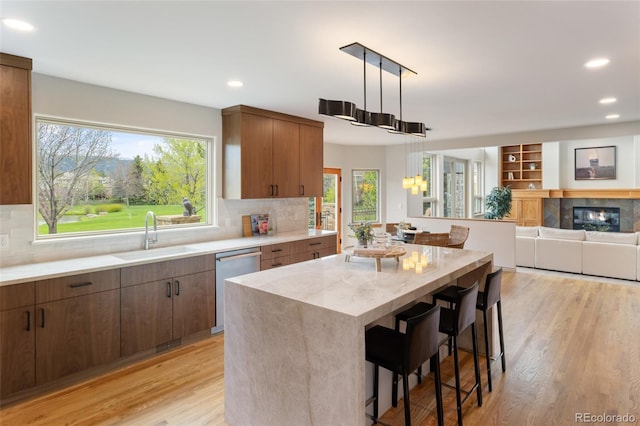 kitchen with pendant lighting, sink, dishwasher, a kitchen breakfast bar, and a center island