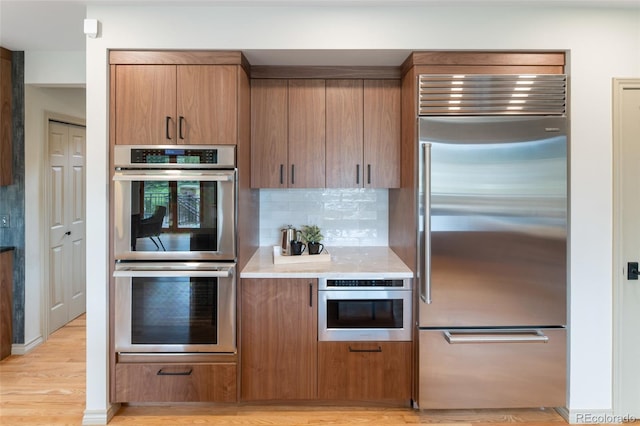 kitchen featuring decorative backsplash, light hardwood / wood-style floors, and appliances with stainless steel finishes