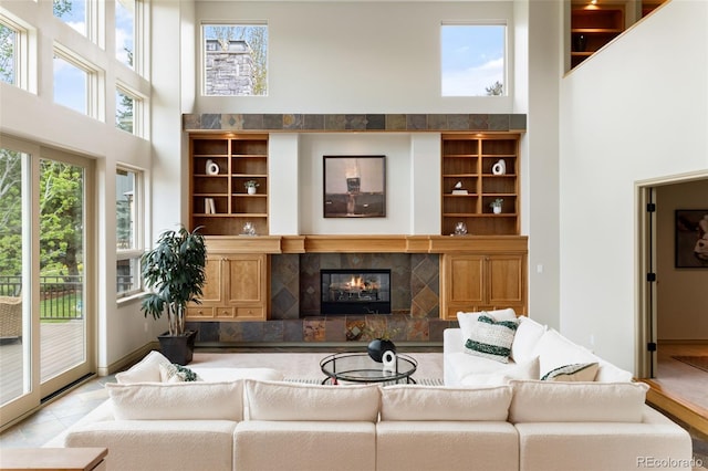 living room with a towering ceiling, a fireplace, and built in features