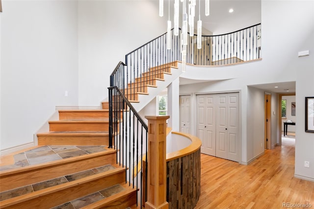 stairway with hardwood / wood-style flooring and a high ceiling