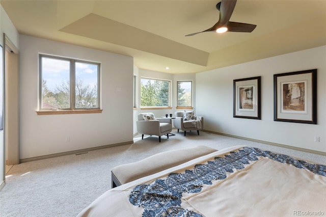 carpeted bedroom featuring a tray ceiling and ceiling fan